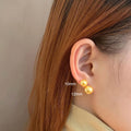 A pair of large geometric pearl stud earrings with an eight-awn star detail on silver settings.