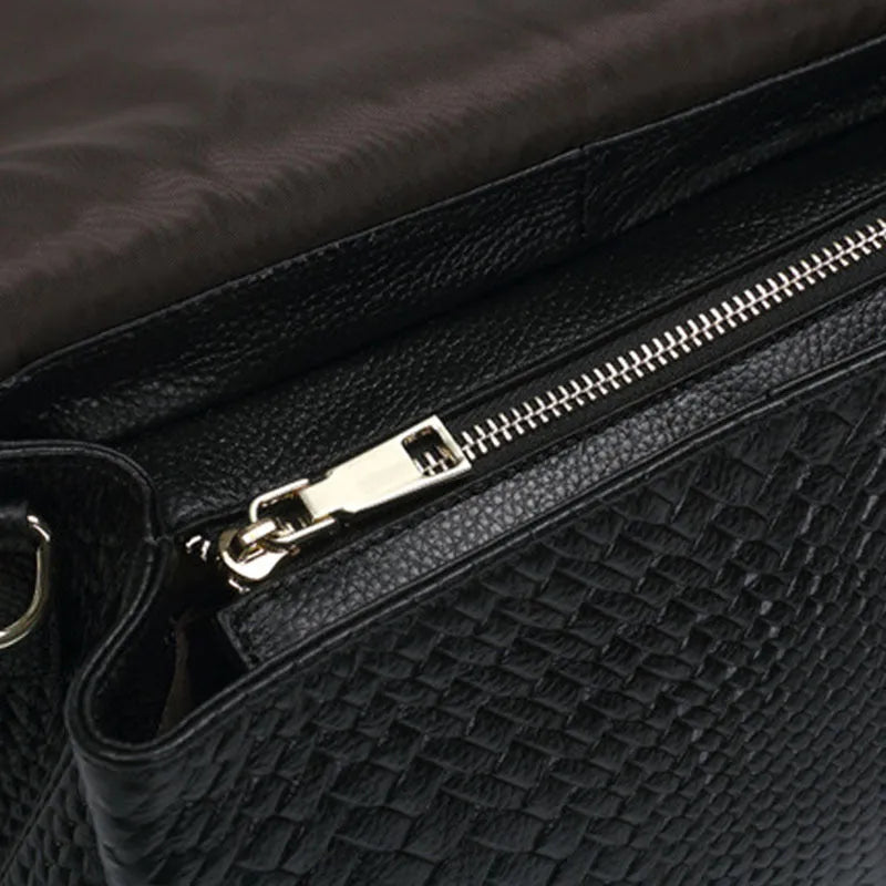 Black genuine leather woven crossbody bag with embossed finish, soft carry handle, and single shoulder strap.