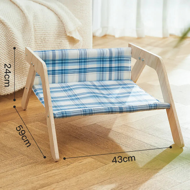 Green wooden elevated cat hammock bed with cloth sling on a light floor.