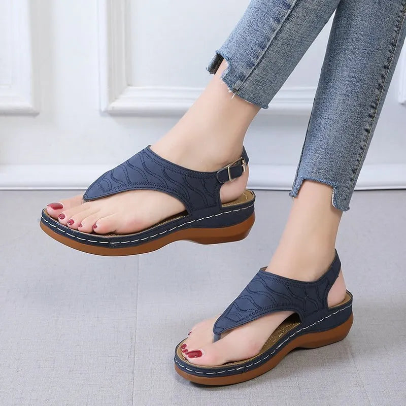 Women's black wedge heel sandals with an adjustable back strap buckle on a white background.