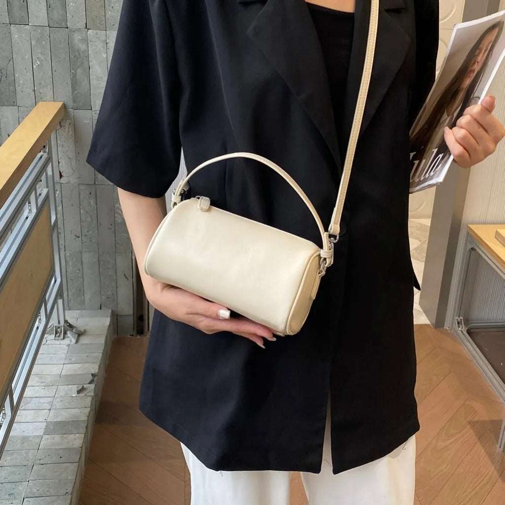 Men's cylindrical leather crossbody phone bag in black, shown with visible stitching and shoulder strap