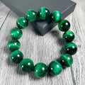 Green tiger eye stone bracelet with polished geometry beads on a wrist, showing the stone's natural banding.