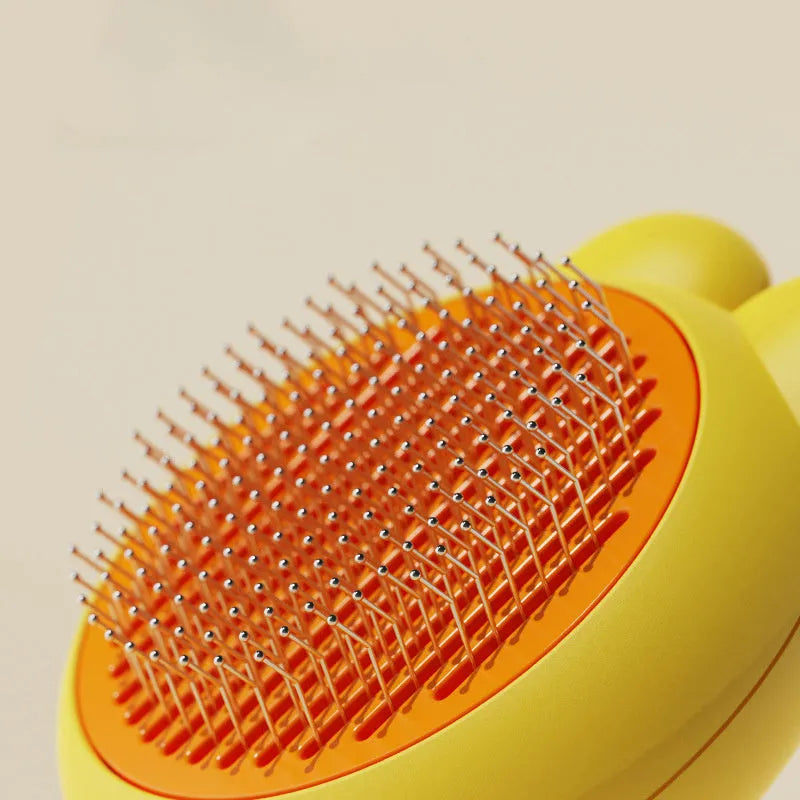Self-cleaning pet brush with release button showing stainless steel comb teeth and coloured handle