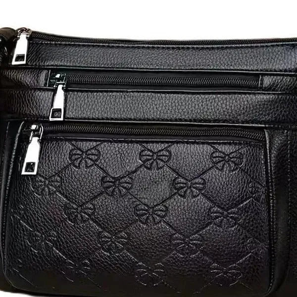 Black women's crossbody bag with embossed butterfly pattern showing phone pocket and external slit