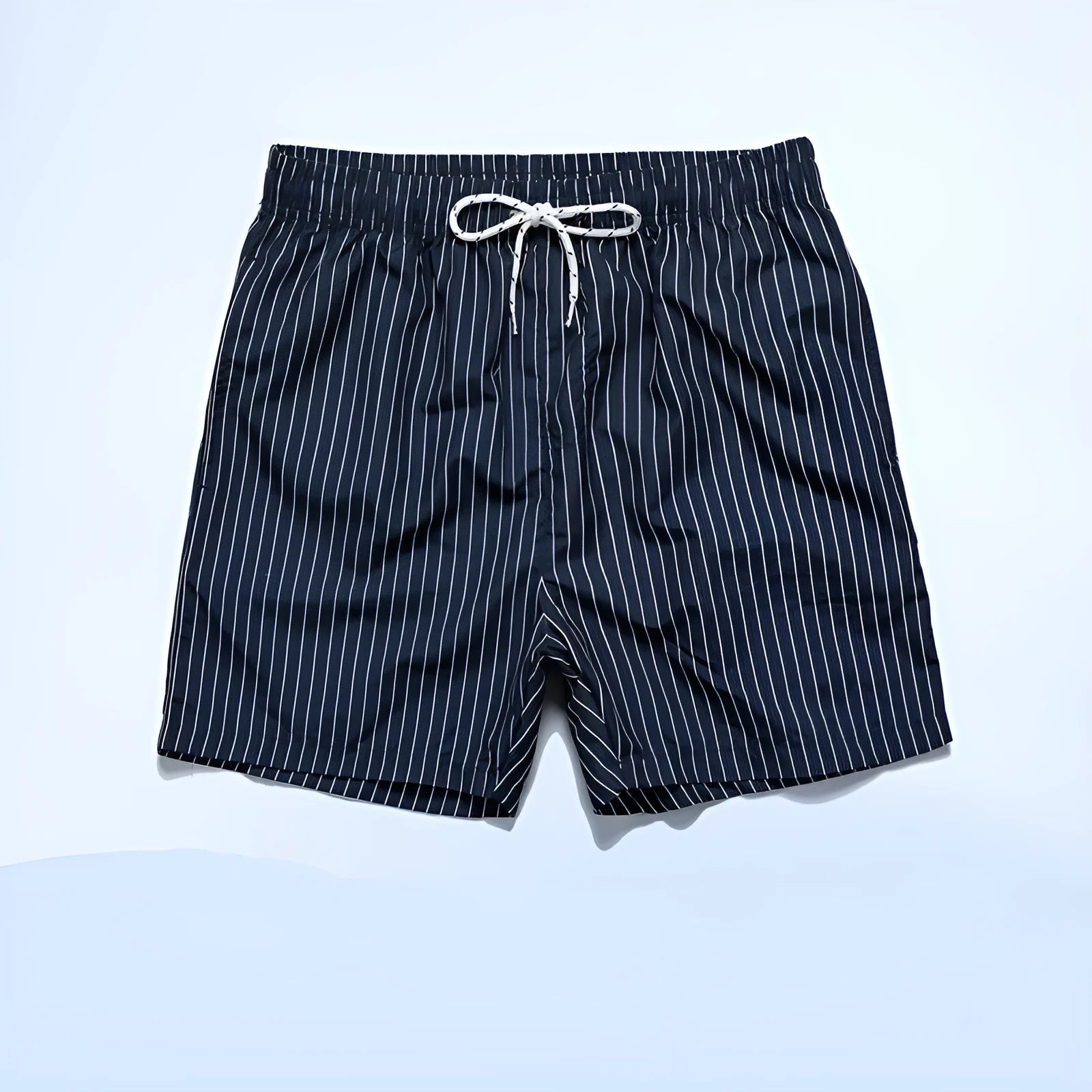 Man wearing grey striped polyester beach shorts with a straight leg opening, on a beach.