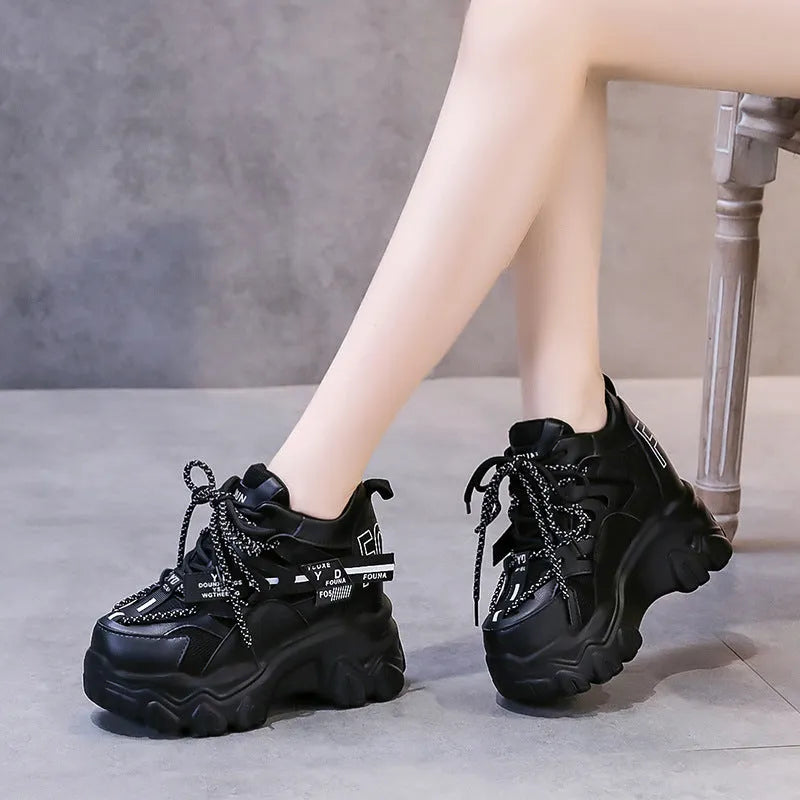 Women's white low-top platform trainers with mesh panels and a black cross-strap over the vamp.