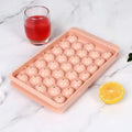 Blue round silicone ice cube tray with 33 grids and a clear lid, shown next to pink version