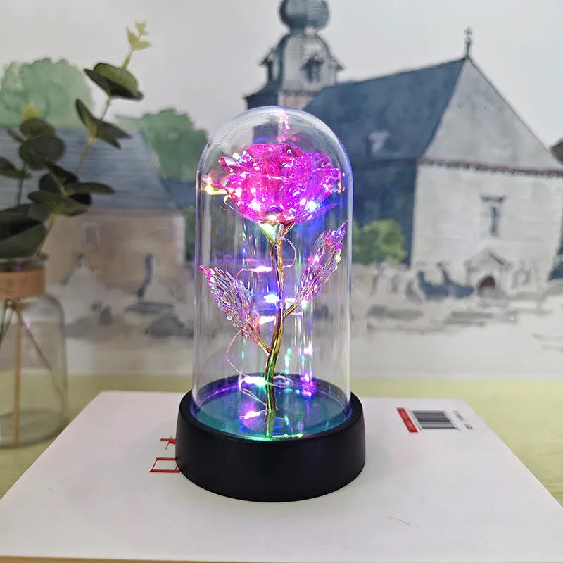 Small glass night lamp with plastic flowers on a black base.