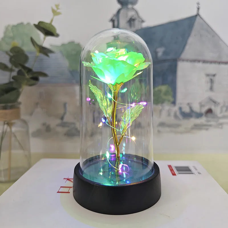 Small glass night lamp with plastic flowers on a black base.