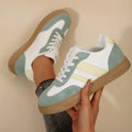 Green women's retro sports pumps with cross straps and leather stitching details