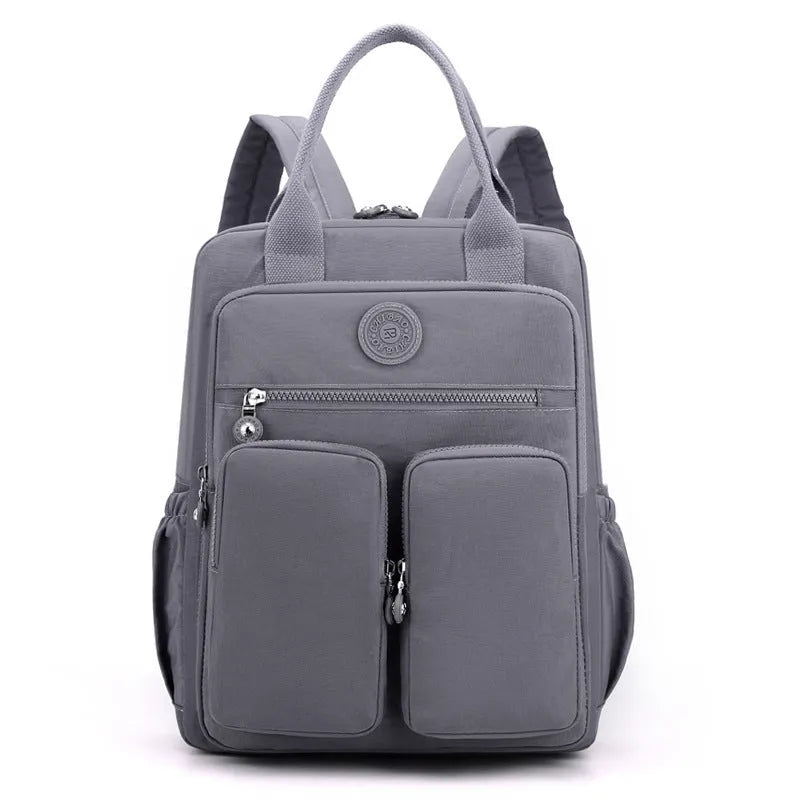 Waterproof nylon women's backpack in grey showing front pockets and internal laptop compartment.