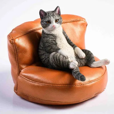 Small resin ornament of a cat sleeping on a sofa for car dashboard or shelf decoration.