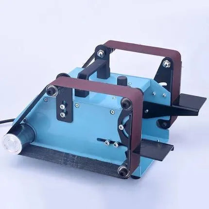 Blue desktop dual-axis belt sander with grinding belt and knife sharpening attachment on workshop bench