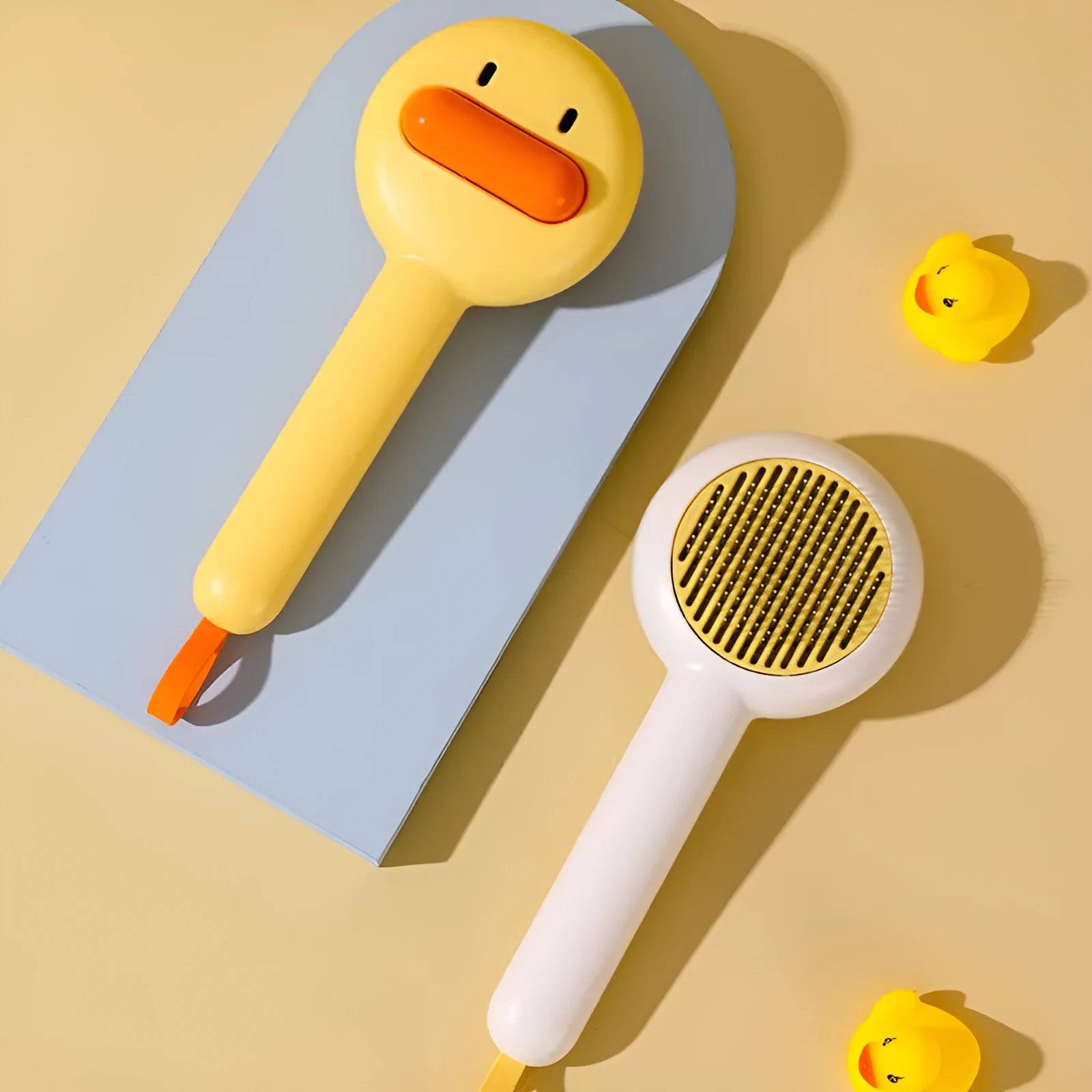 Small yellow duck-shaped pet comb with detachable needle teeth for cat and dog grooming.