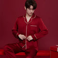 Red matching men's and women's silk sleepwear set with long sleeves and trousers.