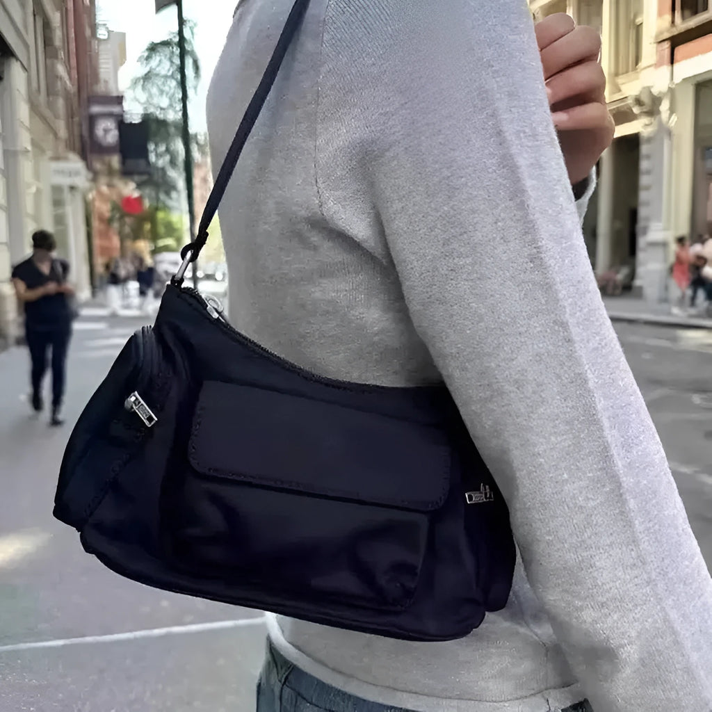 Black nylon shoulder bag with double pockets and side line detail, showing compact dimensions