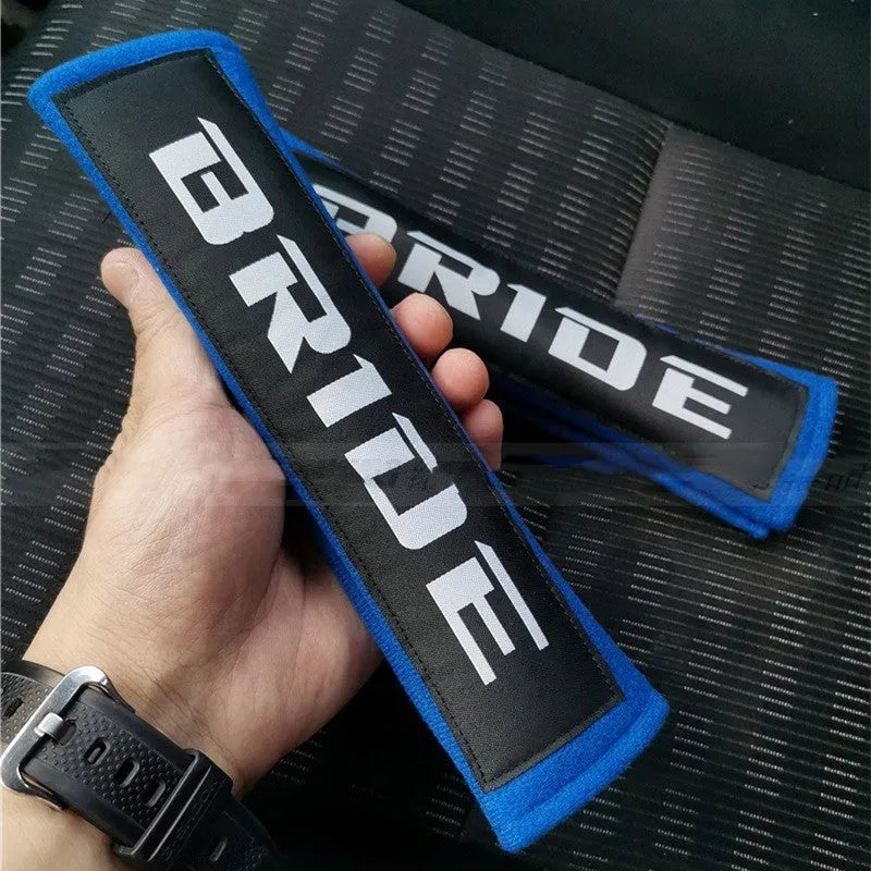Pair of black car seat belt shoulder pads made from cotton sponge cloth, showing embroidery detail.