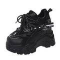 Women's white low-top platform trainers with mesh panels and a black cross-strap over the vamp.