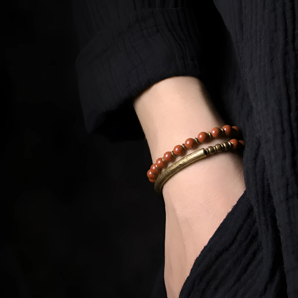 Layered unisex bracelet with water plants agate, red jasper, and obsidian stones on a wrist.