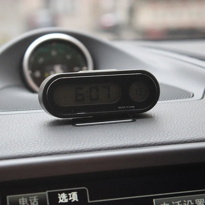 Black electronic car clock thermometer with digital LED display showing time and temperature, featuring an adjustable base.