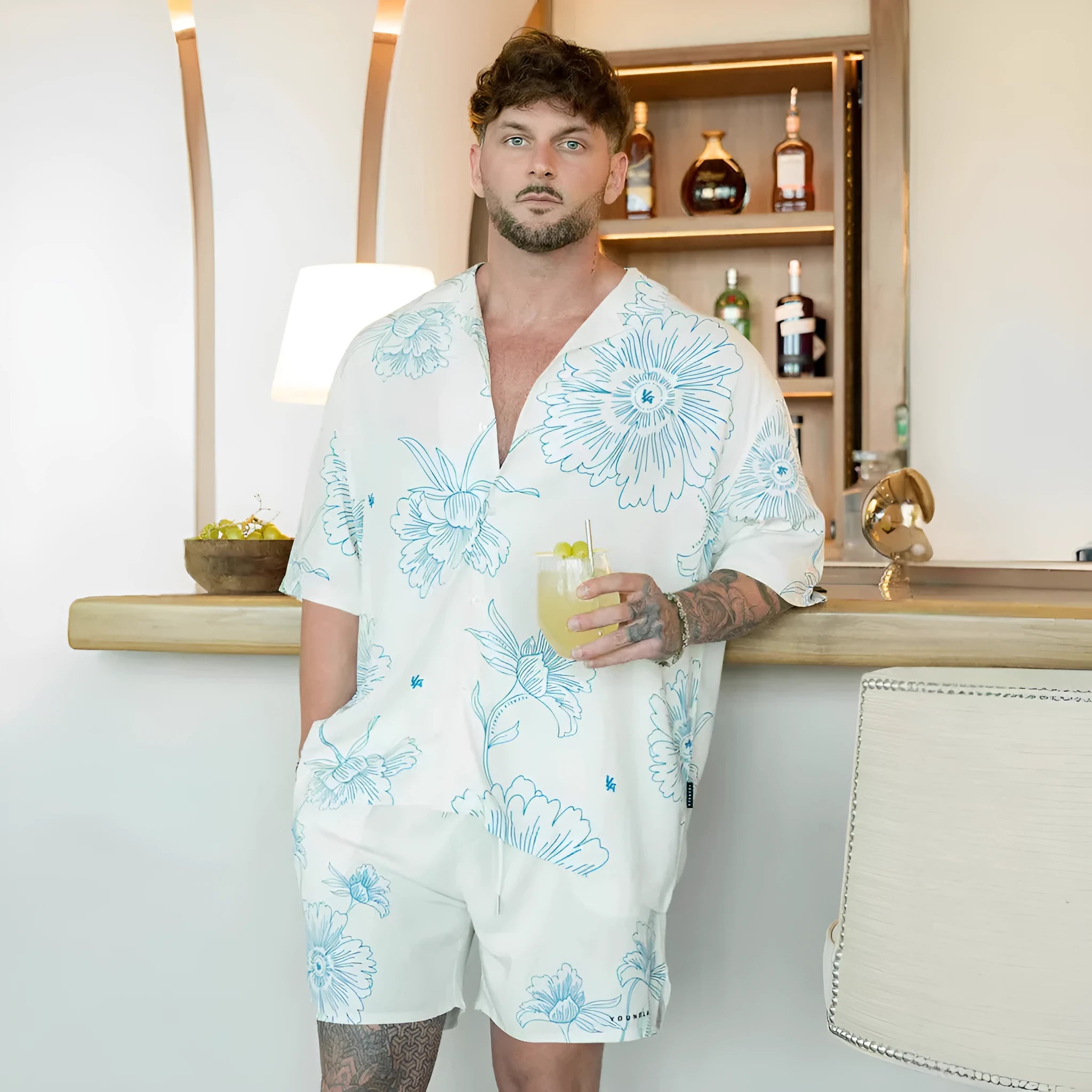Man wearing a loose grey short-sleeve top with a floral print pattern.