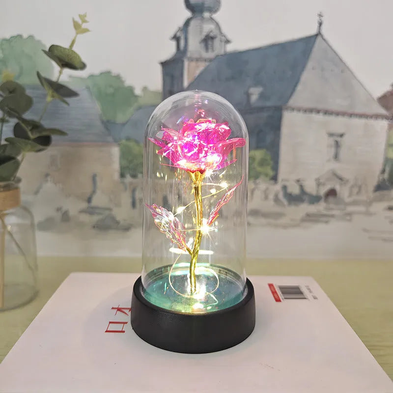 Small glass night lamp with plastic flowers on a black base.