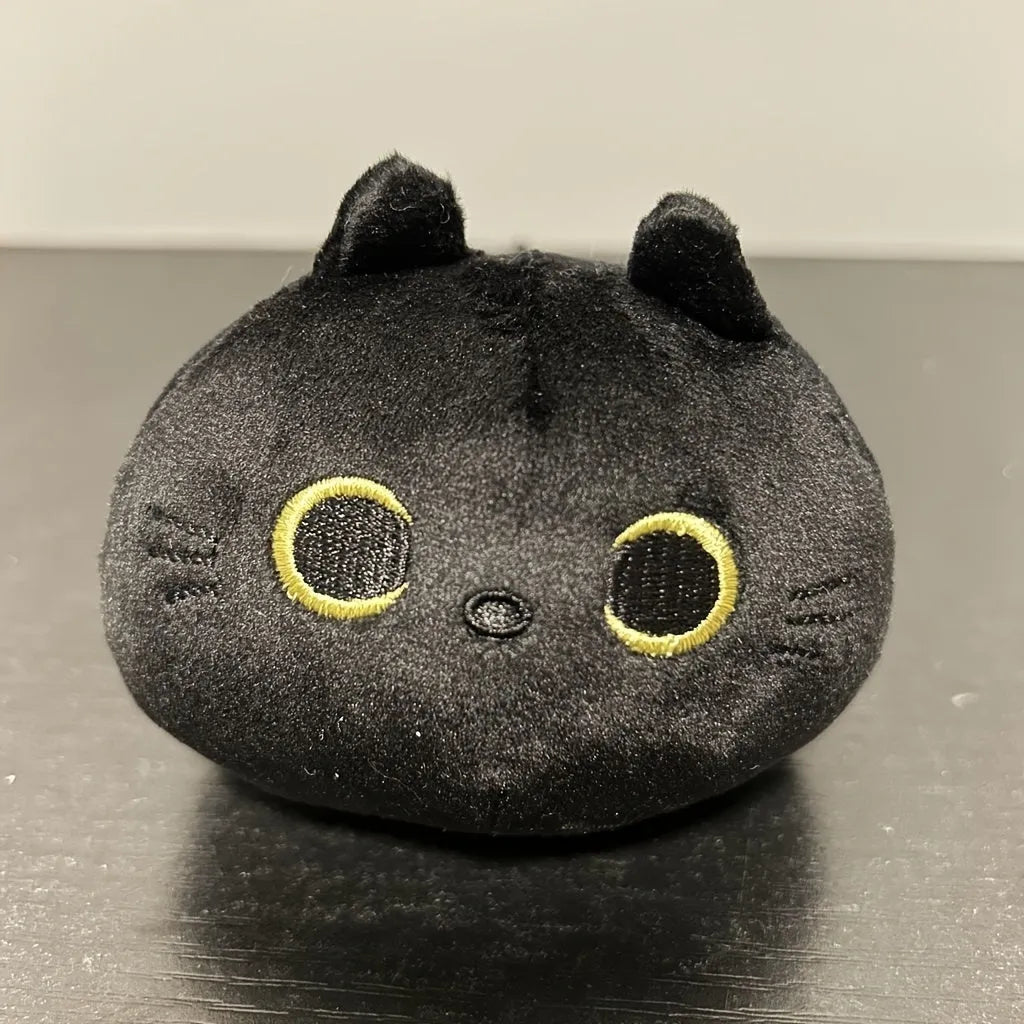 Black fluffy cat plush toy stuffed animal on a sofa, used as a soft cushion.