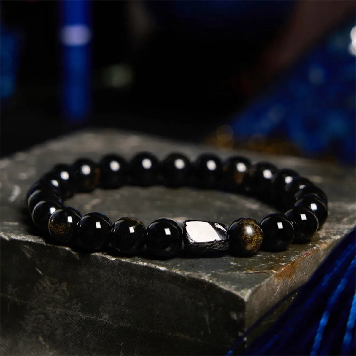 Natural obsidian single ring bracelet with 8mm beads and a metal constellation charm on a white background.