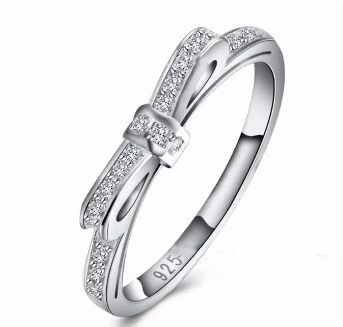 Silver plated bow-shaped ring with clear rhinestone crystal decoration on a model finger