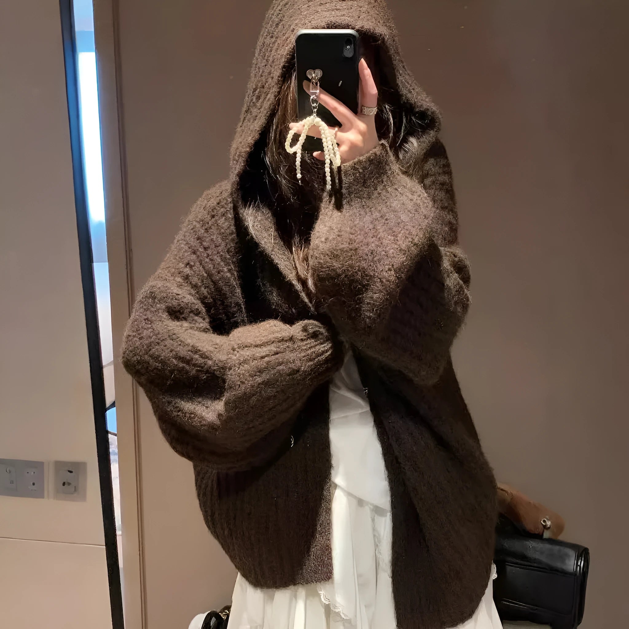 Women's retro-style thick knitted hooded cardigan in dark grey, shown open over a top.