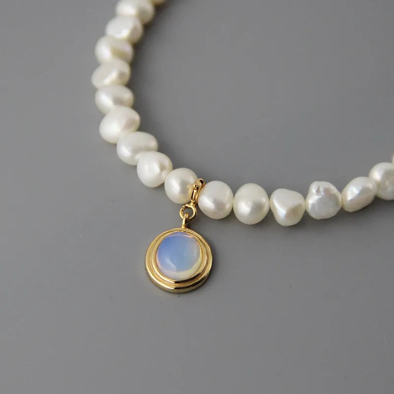 Geometric sterling silver necklace with irregular pearl pendant on a silver chain.