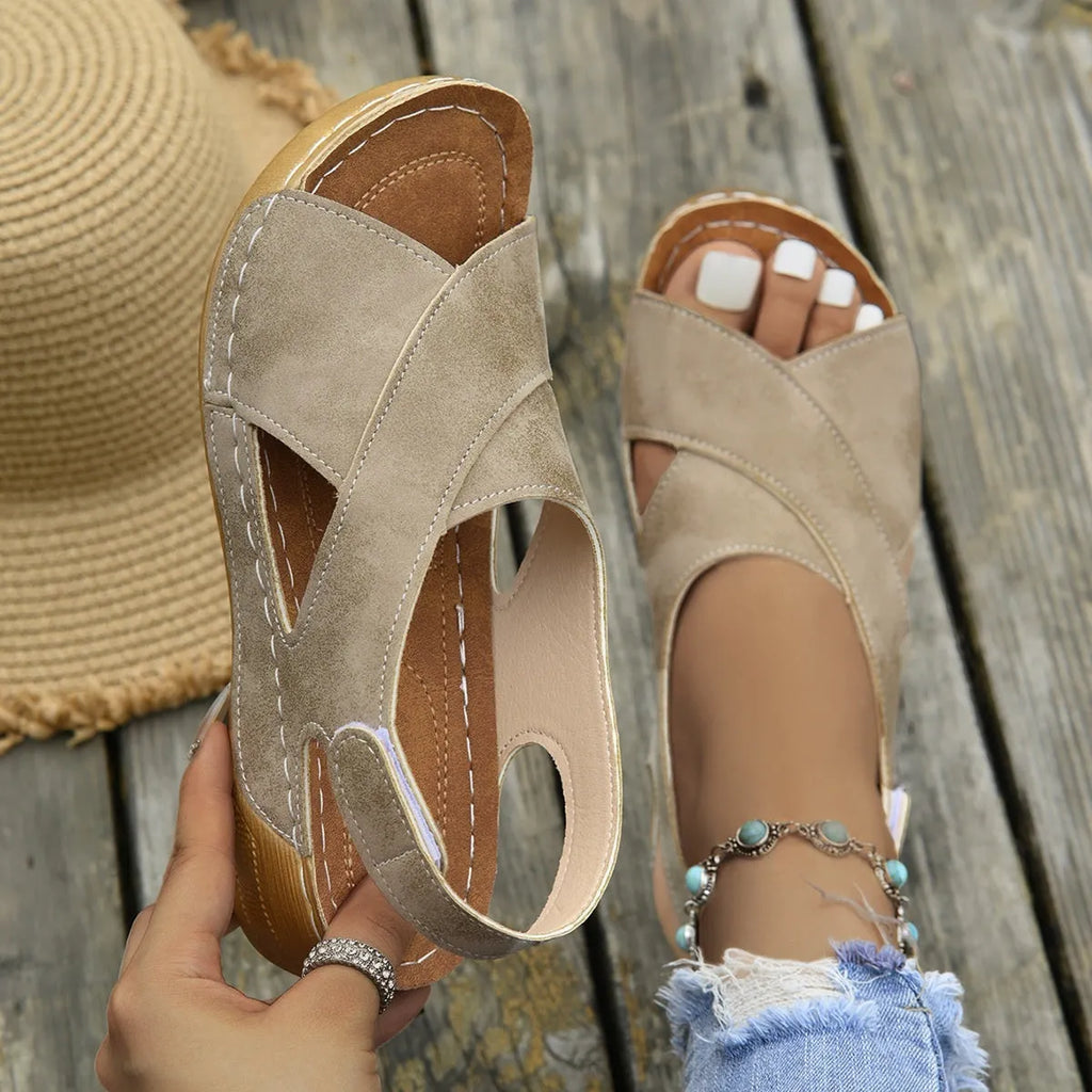 Women's brown Roman sandals with Velcro strap and platform wedge sole on a white background.