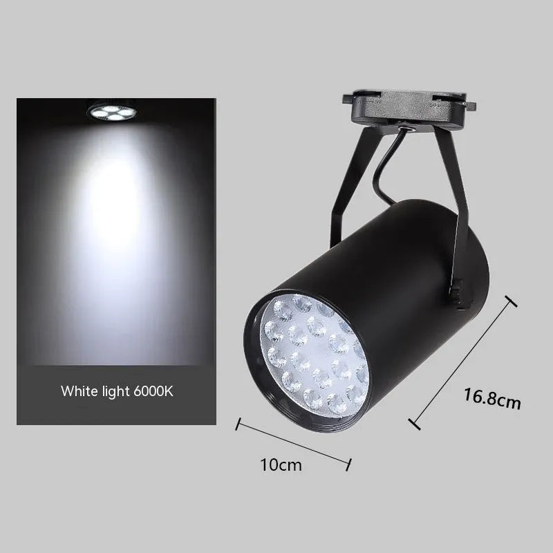 A black aluminium LED track spotlight mounted on a lighting track, angled to illuminate a wall.