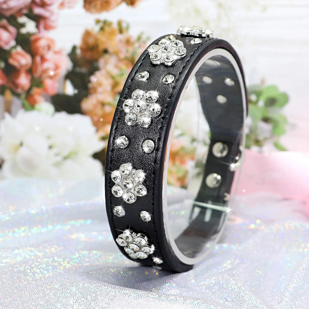 Soft black PU leather dog collar with a sparkling rhinestone flower pattern and silver metal studs, showing the adjustable eyelets and D-ring.