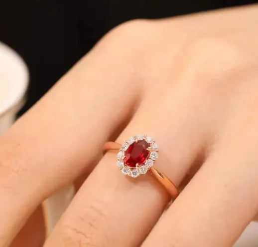 Women's silver ring with gold pigeon design and large red gemstone inlay on a floral pattern band.