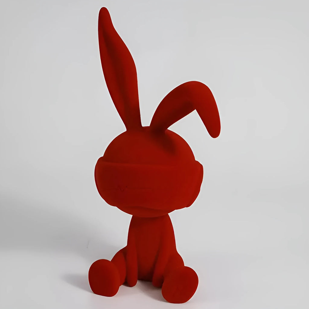 Resin table ornament of a rabbit wearing a suede blindfold with ribbon and tassel detail.