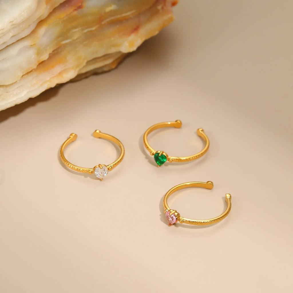 Open ended stainless steel ring with heart-shaped geometric centre and inlaid coloured zircon stone.