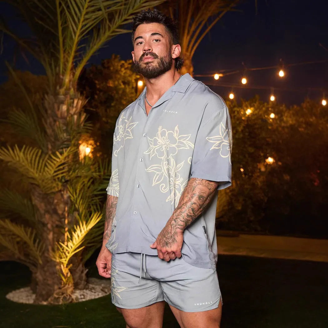 Man wearing a loose grey short-sleeve top with a floral print pattern.