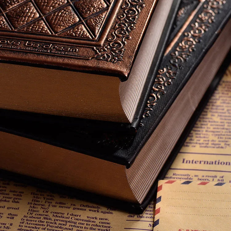 A5 hardback notebook with embossed faux leather cover in bronze colour, shown open on a table.