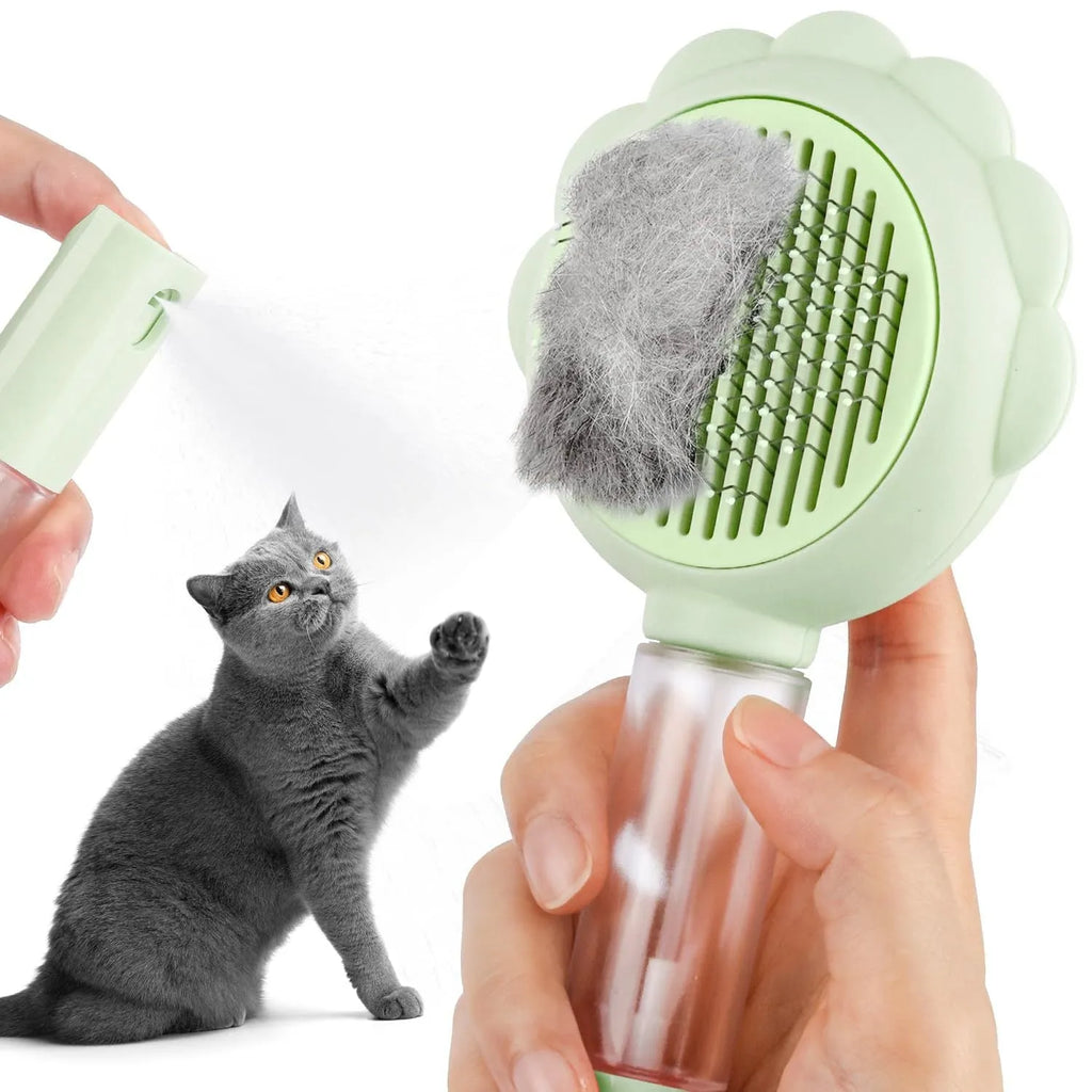 Grey, green, and pink spray cat brush with a release button and curved stainless steel bristles.