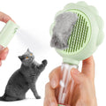 Grey, green, and pink spray cat brush with a release button and curved stainless steel bristles.