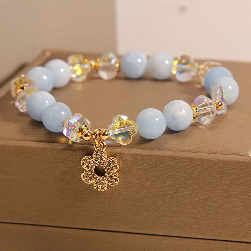 Women's aquamarine crystal bracelet with a four-leaf clover charm and pearl decorative elements.