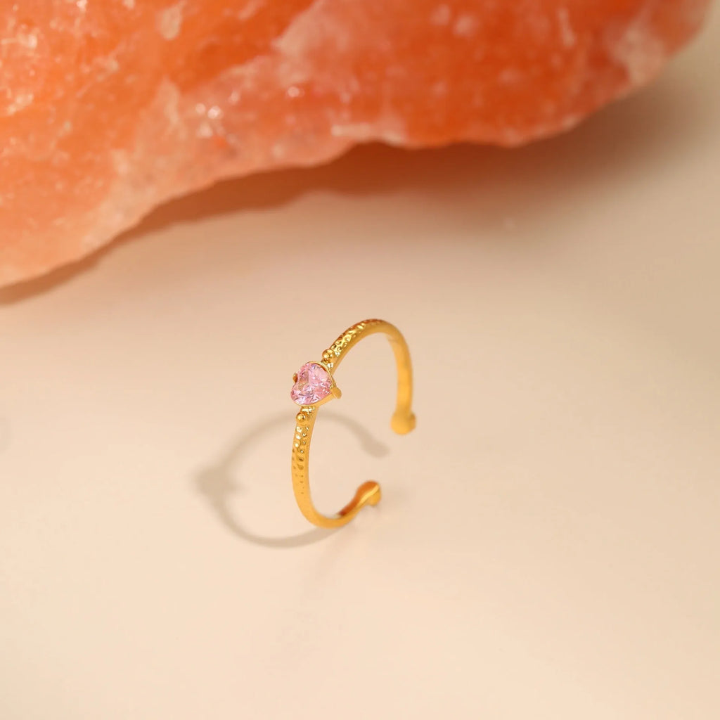Open ended stainless steel ring with heart-shaped geometric centre and inlaid coloured zircon stone.