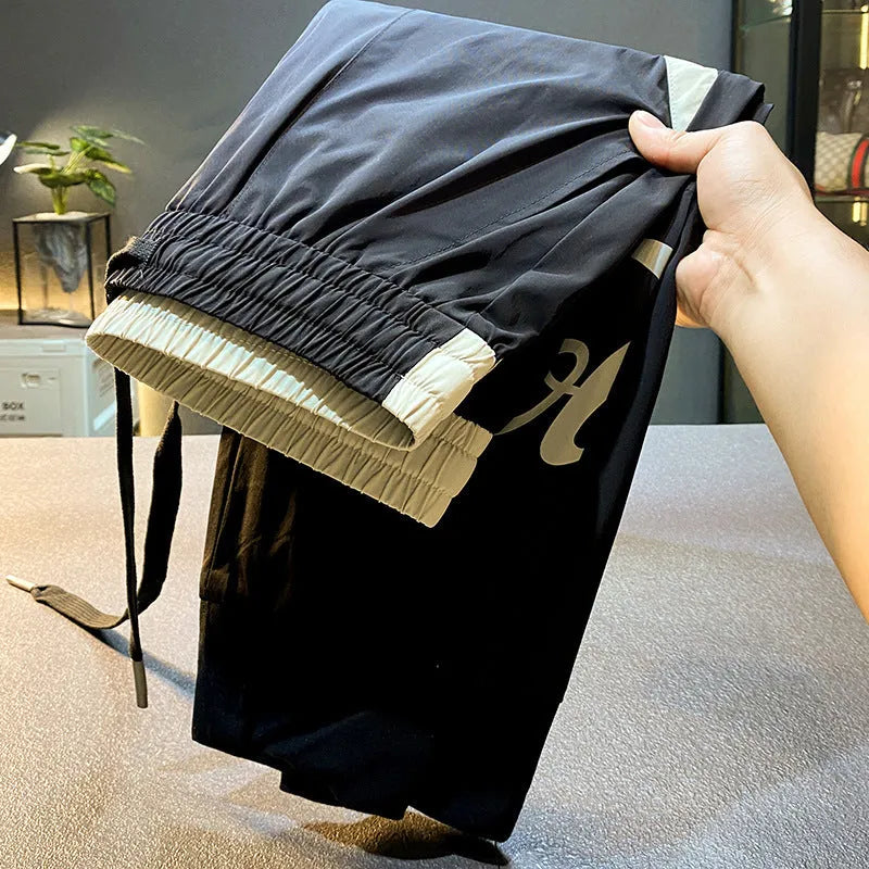 Black men's cropped trousers with banded ankle made from ice silk and cotton fabric.