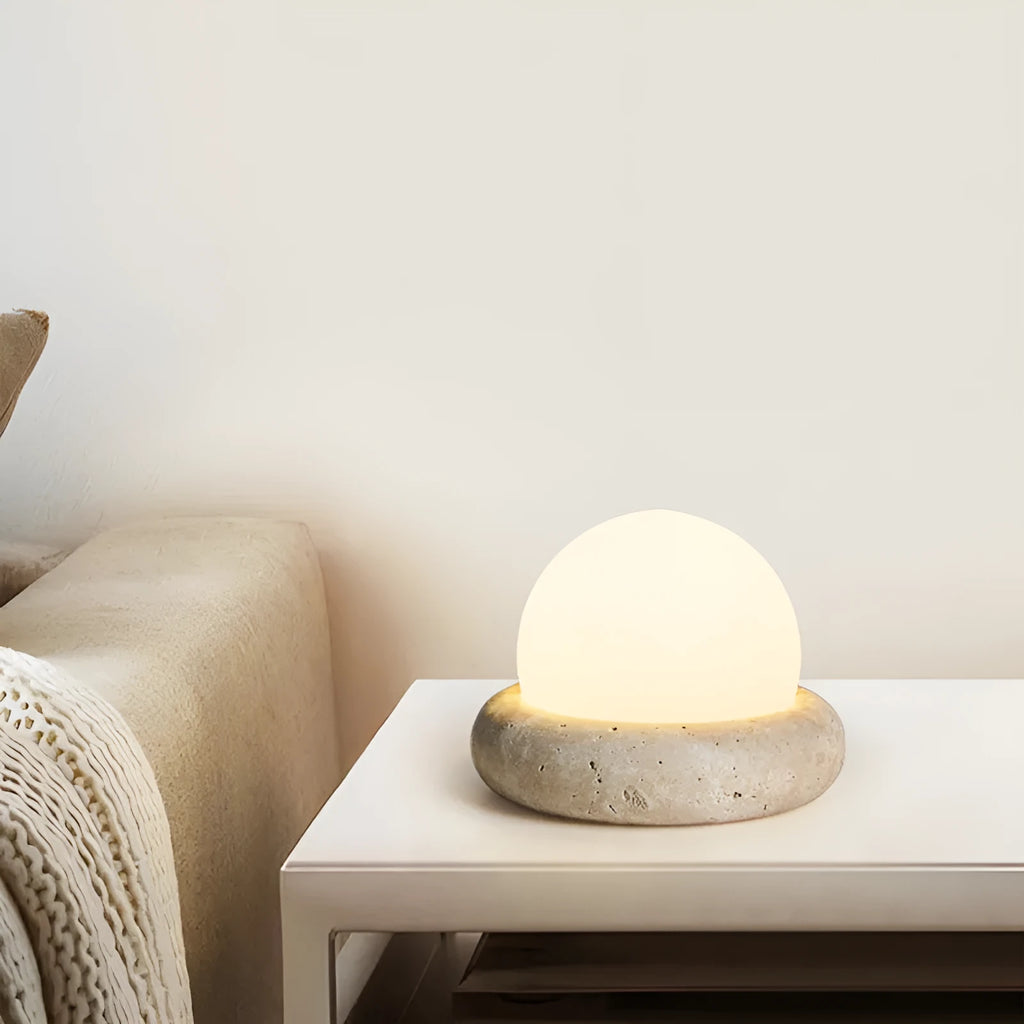 Cream-coloured modern bedside night light with remote control on a table.