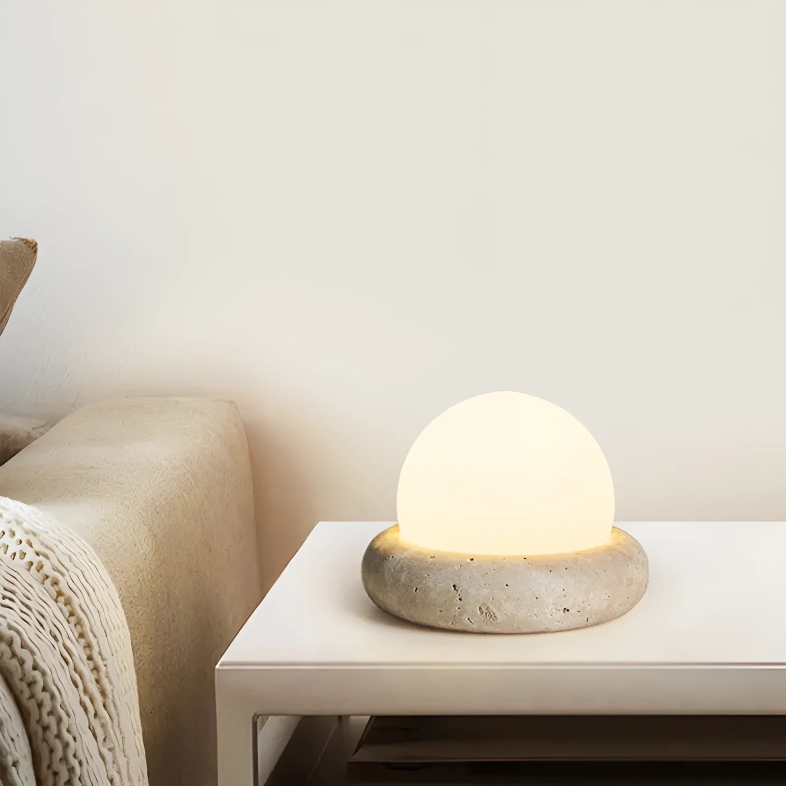 Cream-coloured modern bedside night light with remote control on a table.