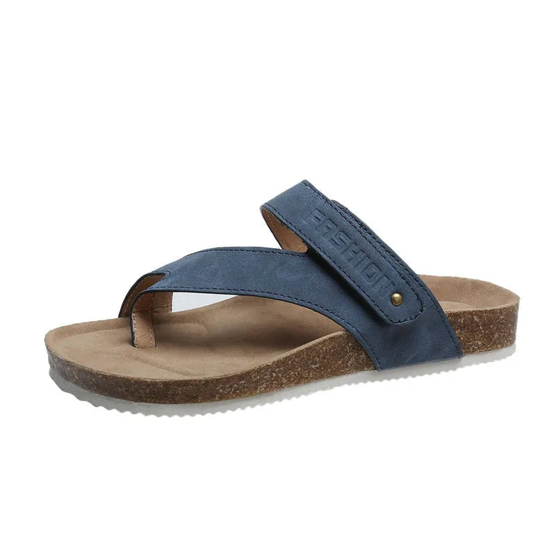 Flat toe ring flip-flops in blue with a thick foam sole on a wooden floor.