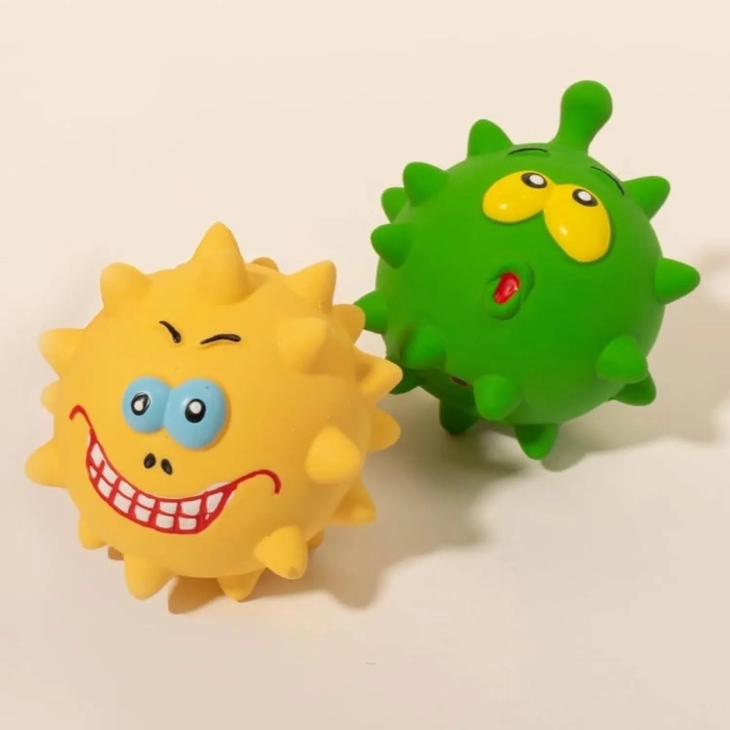 Four colourful latex squeaky dog toy balls with cute animal faces and textured surfaces