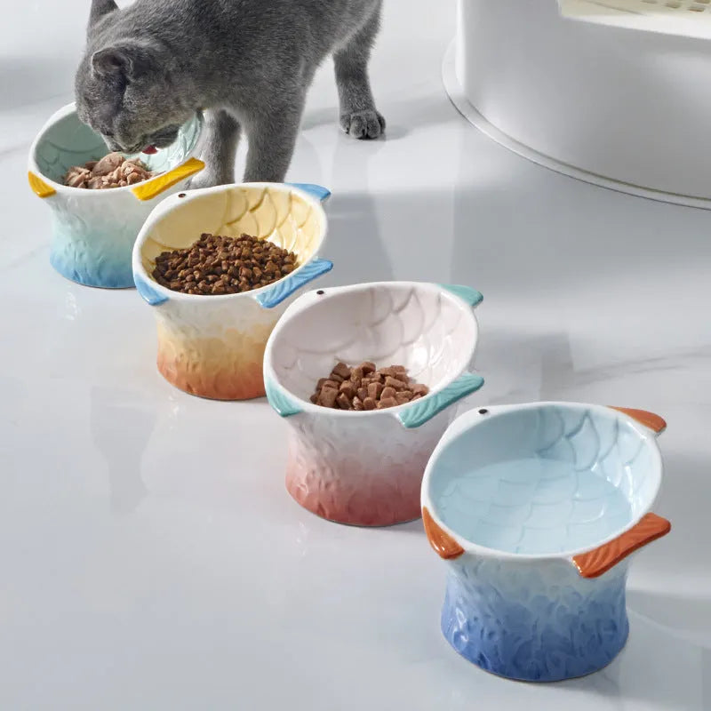 Blue fish-shaped ceramic cat bowl tilted at an angle on a table.