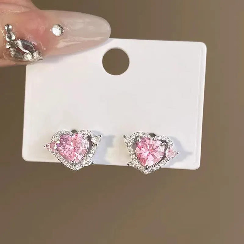 A pair of white heart-shaped stud earrings for women on a plain background.
